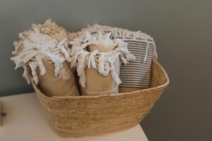 A wicker basket filled with cozy textiles on a neutral background, perfect for home decor.